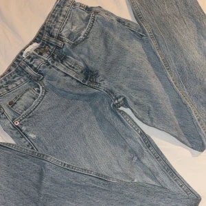 Blå jeans med hål - Säljer ett par snygga lågmidjade blå jeans med hål. Perfekta för en avslappnad stil och kan matchas med nästan vad som helst. Passar både till vardags och fest!