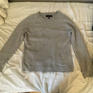 Grå stickad tröja - Mysig grå stickad tröja i normal passform. Perfekt för kyliga dagar med sin mjuka och bekväma känsla. Tröjan har långa ärmar och ribbade kanter vid ärmslut och nederkant. Enkelt att matcha med jeans eller kjol för en avslappnad look.