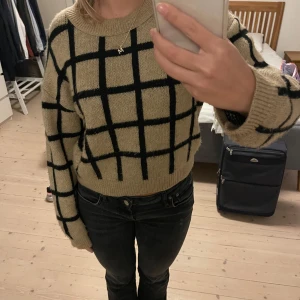 Beige och svart rutig tröja från NAKD - Säljer en superfin beige tröja från NAKD med svart rutmönster. Den är stickad och har långa ärmar, perfekt för höst och vinter. Tröjan är i mycket bra skick och passar perfekt till både jeans och kjol. Skön och stilren för alla tillfällen!