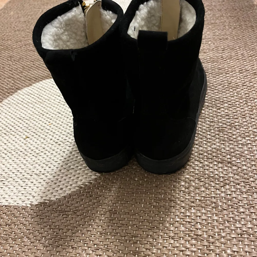 Säljer ett par snygga svarta boots i mocka med guldfärgad dragkedja framtill. De har ett mysigt vitt foder som håller fötterna varma under kalla dagar. Perfekta för höst och vinter! 🖤. Skor.