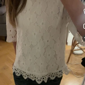 Vit spetsblus - Säljer en superfin vit spetsblus med trekvartsärm. Den har ett vackert blommönster och en söt volangkant längst ner.  både till vardags och fest. Blusen är i mycket bra skick och passar perfekt till jeans