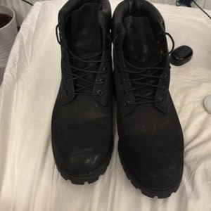 Svarta kängor från Timberland - Säljer ett par svarta kängor från Timberland i bra skick. De har en robust design med snörning och en slitstark sula, perfekt för höst och vinter. Kängorna är gjorda av skinn och har en klassisk look som passar till det mesta. Perfekta för både stad och natur!