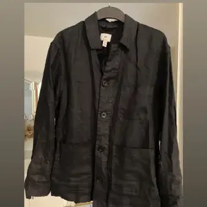 Säljer en stilren svart overshirt från H&M i bra skick. Den har långa ärmar och knappar framtill. Perfekt för höst och vår, och funkar både till vardags och fest. Passar bra över en t-shirt eller tröja för en avslappnad look.