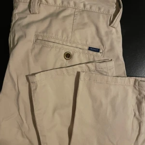 Gant chinos - Ett par väldigt fina beigea chinos, knappen över gylfen saknas. W/30L/30