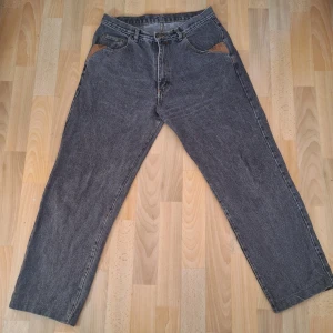Vintage baggy jeans - Gråa Vintage baggy jeans, dom är i fint skick dock är läder detaljerna lite missfärgade. Det står ingen storlek men skulle säga att dom sitter som M, har ni några frågor eller vill ha fler bilder hör av er! Priset går att diskutera 🩷