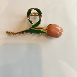 Hårklämma Tulpan blomma håraccessoar hairclaw rosa guld - Hårklämma hårnål hårpin i form av en tulpan. Den är ca 11 cm lång och 4 cm bred som ni kan se på bilderna. Perfekt håraccessoar för både vardag och fest Helt ny och aldrig använd