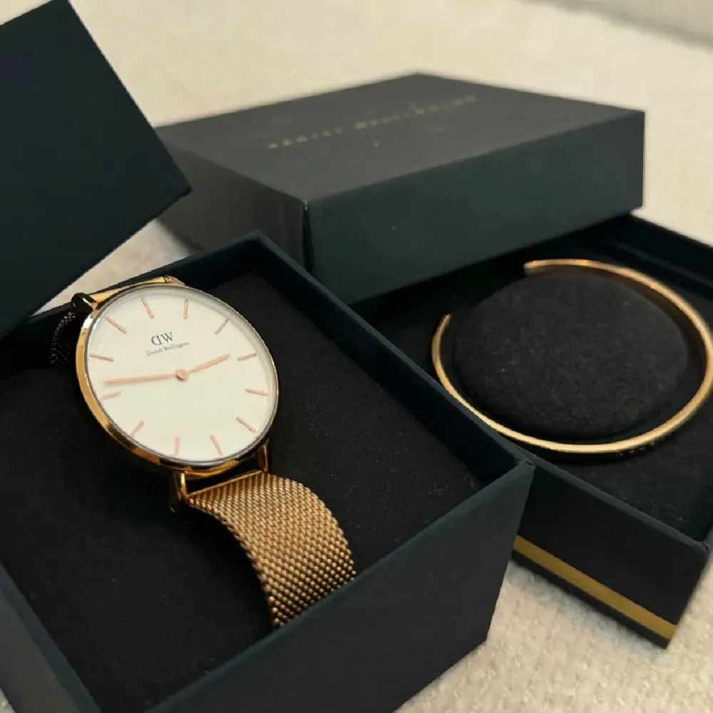 Säljer en stilren klocka från Daniel Wellington med guldigt mesharmband. Medföljer ett matchande guldarmband för en komplett look. Klockan är i nyskick och kommer i originalförpackning. Nypris för armbandet: 699kr, nypris för klockan: 1399kr. Säljer båda för 899kr.. Accessoarer.