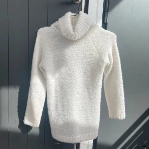 Vit fluffig polotröja - Mysig vit polotröja i fluffigt material, perfekt för kyliga dagar. Den har en hög krage och långa ärmar, vilket gör den superbekväm och varm. Perfekt för höst och vinter!