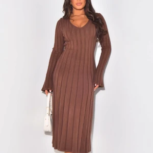 Brun ribbad långklänning - Säljer en superfin brun ribbad långklänning med v-ringning och långa ärmar. Klänningen har en knytning i midjan som ger en snygg passform. Perfekt för höst och vinter, både mysig och stilren! Helt ny oöppnad!