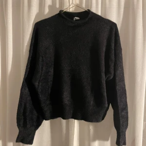 Svart tröja från Weekday - Säljer en mysig svart tröja. Den är perfekt för kyliga dagar med sin mjuka och fluffiga textur. Tröjan har långa ärmar och en klassisk passform som funkar till allt. Perfekt för både vardag och fest!