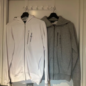 Sailracing Zip Hoodie - Säljer nu två stycken riktigt snygga sailracing hoodies i färgerna vit och grå. Den vita är i nyskick och aldrig använd och den gråa är använd under Max 3 månader och i mycket bra skick. 