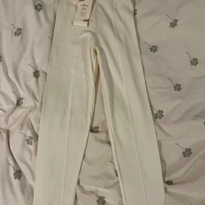 Vita byxor - Säljer ett par stilrena vita byxor. De är högmidjade och en tight passform som ger en snygg och elegant look. Perfekta för både vardag och fest!