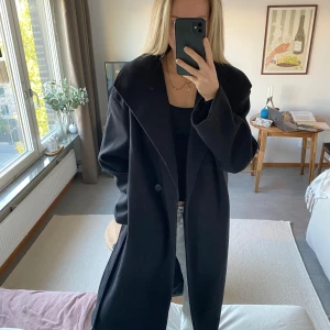 Lång Kappa NA-KD - Lång kappa (slutar på mitten av vaden och är 173), svart från NA-KD. Passar perfekt nu på hösten. Använd några gånger inget större fel. Lite oversized i modellen.  Nypris var över 1000kr 