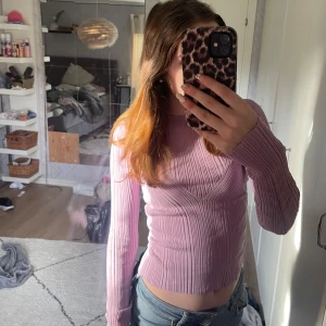Ljuslila ribbad tröja från NA-KD - Säljer en superfin ljuslila ribbad tröja från NA-KD. Den har en öppen rygg och långa ärmar, vilket gör den perfekt för både vardag och fest. Tröjan är i storlek XS och sitter tight, vilket ger en snygg siluett. Perfekt för vår och sommar!