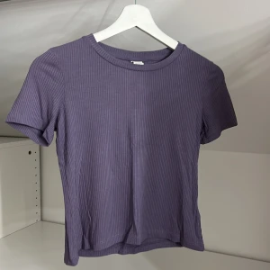 Lila ribbad topp från Lindex - Säljer en lila ribbad topp från Lindex i storlek 134/140. Toppen har korta ärmar och en rund halsringning.