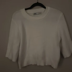 Vit kortärmad stickad tröja från Zara - Säljer en stilren vit stickad tröja från Zara. Tröjan har trekvartsärmar och en rund halsringning. Perfekt för en avslappnad och trendig look.
