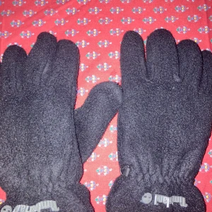 Svarta fleecehandskar från Timberland - Säljer ett par svarta fleecehandskar från Timberland. De är varma och perfekta för kyliga dagar. Handskarna har elastiska muddar för bättre passform och Timberland-loggan syns tydligt på dem.