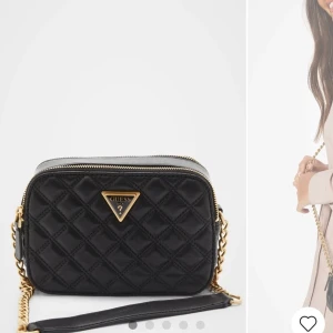 Svart axelväska från Guess - Snygg svart quiltad axelväska från Guess med guldfärgade kedjedetaljer och dragkedja. Perfekt för att ge en elegant touch till din outfit. Väskan har en klassisk design med det ikoniska Guess-emblemet på framsidan. Helt oanvänd och ny!