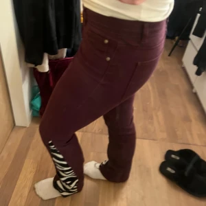 Vinröda jeans med zebramönster - Snygga vinröda byxor med unika zebramönstrade detaljer längs benen. Jeansen är omsydda till bootcut. Perfekta för att sticka ut i mängden!💕