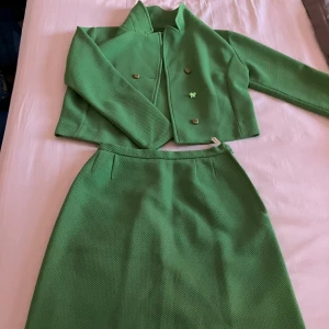 Vintage retro set från 70-talet  - Snygg kjol med matchande jacka. Kjolen har en klassisk A-linjeform och är tillverkad i ett texturerat material. 