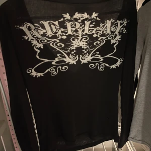  Replay tröja - Snygg svart långärmad tröja från Replay med tryck i vitt på både fram- och baksida. Tröjan har en djup v-ringning och knappar framtill, vilket ger en stilren look. Perfekt för en avslappnad stil.