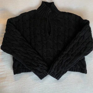 Svart stickad tröja från NA-KD - Säljer en svart stickad tröja från NA-KD med kabelstickat mönster och hög krage. Tröjan har långa ärmar och ribbade detaljer vid krage och ärmslut.