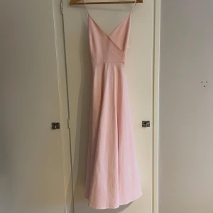 Vacker klänning med rosett - Söt rosa klänning med rosett detalj där bak!Rosetten knyts och justeras av en själv. Mycket gott skick, använd endast 1 gång!! Den är altererad där fram, se bild 4+5. Men lätt att sprätta upp och det är ingenting som syns på framsidan💓💓