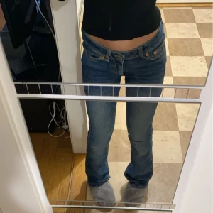 Blå jeans med låg midja - Ett par skitsnygga blå jeans med låg midja och en otrolig design på baksidan. De är bootcut och är perfekta för en avslappnad stil. Jeansen har en dragkedja och knapp framtill.