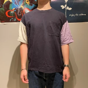 Flerfärgad t-shirt från H&M - Säljer en cool flerfärgad t-shirt från H&M med oversized passform. T-shirten har en bröstficka och korta ärmar i olika färger: mörkblå, ljuslila och vit. Perfekt för en avslappnad stil.