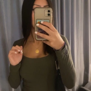 Olivgrön långärmad topp - Snygg olivgrön långärmad topp med en fyrkantig halsringning. Perfekt för en stilren och enkel look. Passar bra till både jeans och kjol.