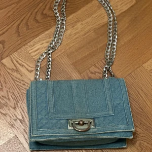 Jeans axelarmsväska väska från Gina tricot.  - Jeans axelarmsväska väska från Gina tricot. Säljer denna väska i acceptabelt skick.Köpte begagnat för 79 kr säljer för 30kr.Den har ett hål till. Fråga gärna om bilder pris kan diskuteras.