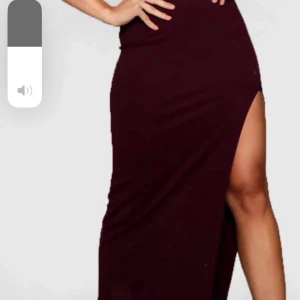 Vinröd långklänning med slits - Elegant vinröd långklänning med hög slits. Perfekt för en kväll ute eller en speciell tillställning. Klänningen har en figurnära passform som framhäver silhuetten.