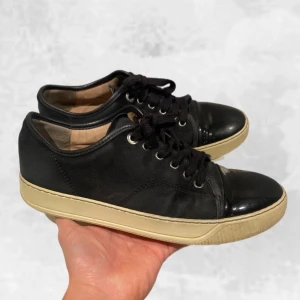Lanvin skor svarta - Skohylla rensining. Lanvin sneakers glossy toe cap svarta. Skick: 7/10, använt men sparsamt skick, mockan är använd & stygn som gått upp (se sista bild). Nytvättade med sneakerstvättens tvättkit! Även sprillans nya skosnören på! storlek: UK 6 som motsvarar 40-41. Nypris inköpt för 4 300 kr! Medföljer original boxen givetvis vid köp! Hör av dig vid frågor eller funderingar. Mvh Oliver;)