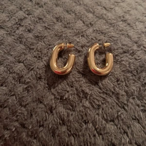 Guldiga örhängen - Snygga och stilrena guldiga örhängen i en chunky design. Perfekta för att ge en touch av elegans till vilken outfit som helst. Lätta att matcha med andra smycken.