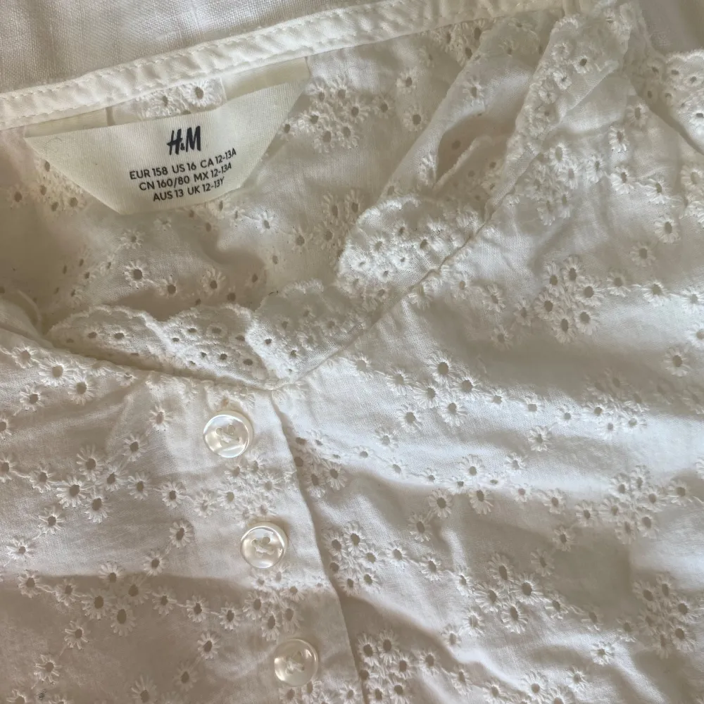  En söt, vit och blommig linne från H&M i storlek 158 barn avdelning. Den har små pärliga knappar, och en babydoll passform! Det är ett lätt material. I bra skick🤗Bra kvalitet🥳. Köpte för 250. Pris kan diskuteras 🙌🏼😁❤️. Toppar.