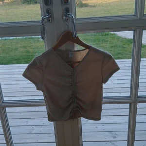 Tröja👚 - En beige tröja som har render på sig. Den är kort ermad