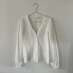 Blus Vila - Vit blus från Vila med fina detaljer kring hals och ärmar. Storlek 34.