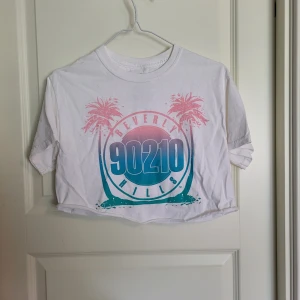 Vit tshirt - Kort, avklippt t-shirt mes tryck. Osäker på vart den kommer ifrån. Använd fåtal gånger så i fint skick!