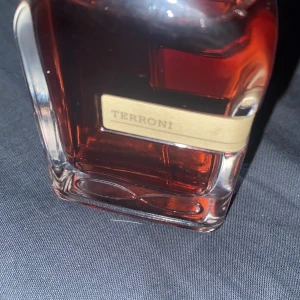 Terroni parfym från Orto Parisi - Skriv innan köp. Säljer en exklusiv parfym från Orto Parisi, Terroni. Flaskan har en elegant design med en djup röd vätska och en unik kork med textur. Perfekt för den som söker en distinkt och minnesvärd doft.