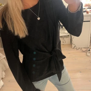 Svart långärmad topp med knyt - Snygg svart långärmad topp med knyt i midjan💕🩷lite glittrig som syns på bilderna!!  passar mig som har S också