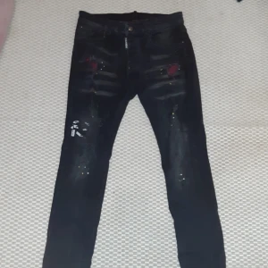 Svarta jeans från Dsquared2 - Hej jag säljer Snygga svarta jeans från Dsquared2 med coola slitningar och färgstänk. Priset kan diskuteras 