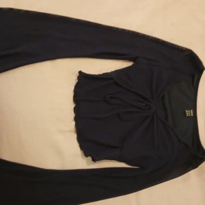 Svart långärmad topp från Shein - Snygg svart långärmad topp från Shein i storlek XS. Toppen har en åtsittande passform med en fin knytdetalj framtill och vågig nederkant. Perfekt för en stilren look.