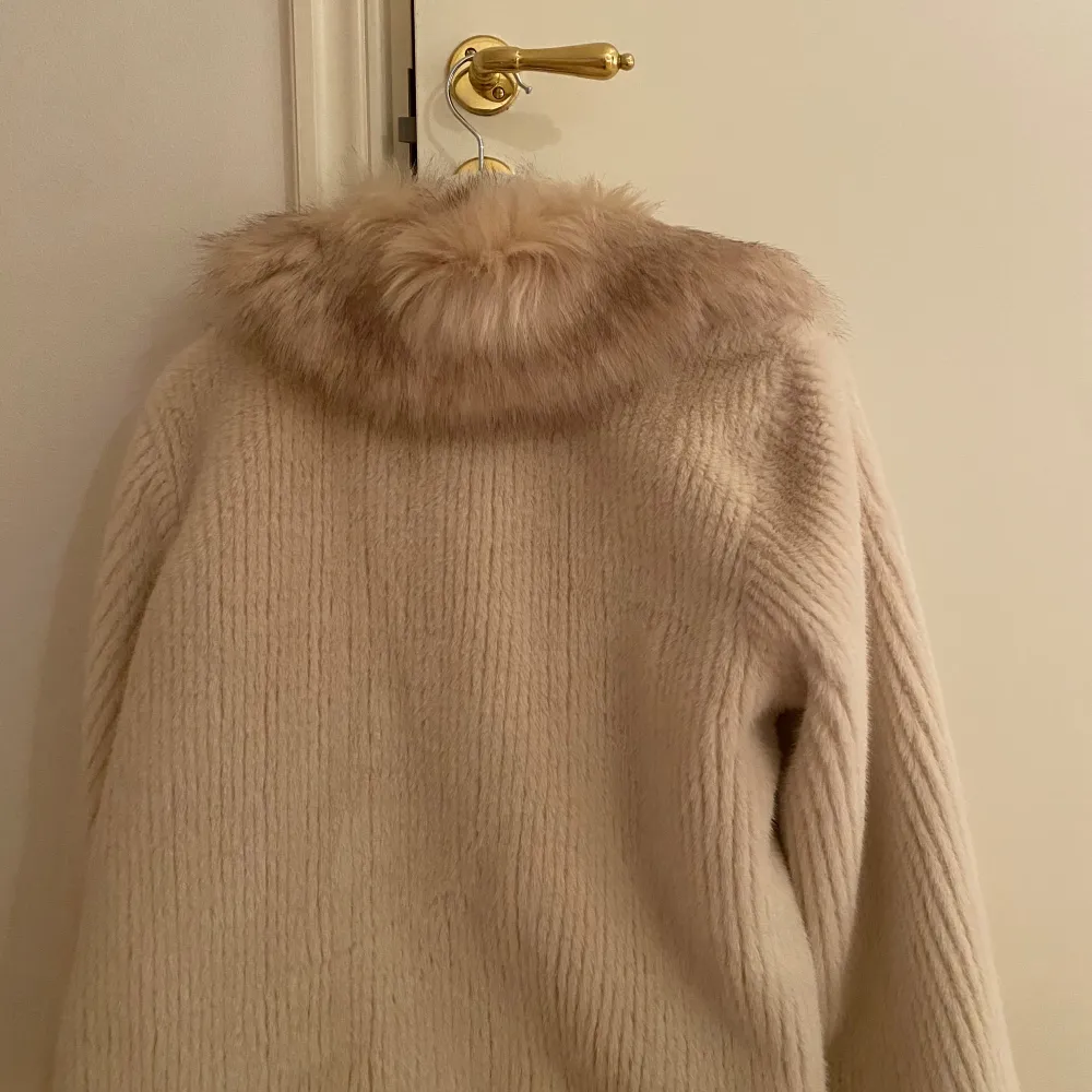 Säljer en elegant beige kappa med en lyxig pälskrage. Jackan är tillverkad i Italien och har en stilren design med långa ärmar och en mjuk, ribbad textur. Perfekt för att hålla sig varm och snygg under kyliga dagar. 🧥✨Aldrig använd och köpt i en fin butik i Barcelona i höstas! Köpt för 1000kr men säljer för 790kr💫 . Takit.