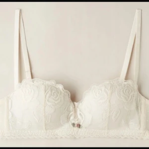 Intimissimi bh - Elegant vit bh med vackert blommönster i spets. Den har justerbaras axelband och en liten rosett framtill. 