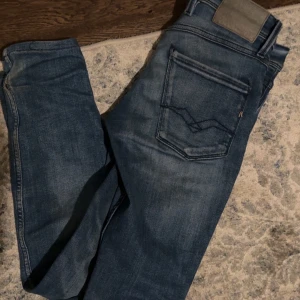 Feta jeans från replay  - Säljer nu dessa asfeta snygga blå replay jeans med klassisk design och knappgylf. Perfekta för en avslappnad stil. De har en lätt tvättad look.  De är köpta för 1899 och är i 28/32 två små defekter som finns på bild 3&4 men annars är de i otroligt skick. Hör av er vid frågor 🙌