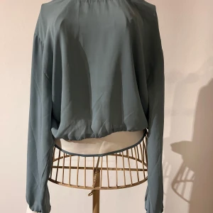 Gönblå tunn tröja från Bik Bok - Snygg grönblå tröja från Bik Bok i storlek XS. Tillverkad i tunn/skir polyester med långa ärmar och elastisk nederkant. Perfekt för en cool look. Tröjan är enbart använd vid ett tillfälle.