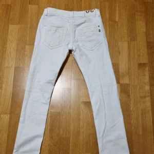 Dondup jeansbyxor - Snygga vita jeans från Dondup med klassisk femficksdesign och knappgylf. De har en rak passform och är tillverkade i Italien. Den enda skavanker på byxan är att i den ena framgick är det hål.