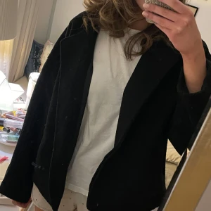 Svart jacka från Nelly - Snygg svart jacka från Nelly med knappar framtill. Jackan har en stilren design med långa ärmar och två fickor. Perfekt för en elegant look. Oversized 