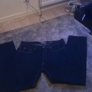 Mörkblå jeans från Dressmann - Snygga mörkblå jeans från Dressmann i regular fit. Klassisk design med fem fickor och knappgylf. Perfekta för en stilren look.          PRIS KAN DISKUTERAS 