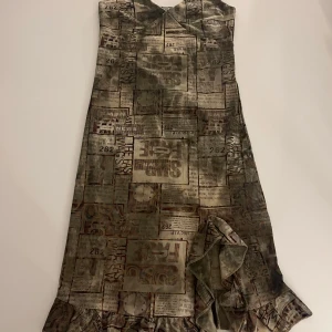Mönstrad vintage klänning med tidningstryck - Unik vintage klänning med tidningstryck i grått och khaki. Köpt utomlands! One size men passar helst xs-m.
